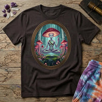 A mushroom-capped alien meditating on a mossy rock in an oval forest frame, on a Dark Chocolate unisex t-shirt