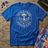 The Quiet Work Beneath It All badge with a mushroom above the soil line and its roots below, on a Royal blue unisex t-shirt
