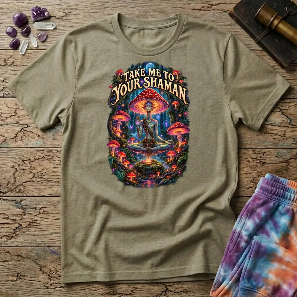 Take Me to Your Shaman lettering above a neon amanita-crowned figure meditating in a glowing forest, on a Sand unisex t-shirt