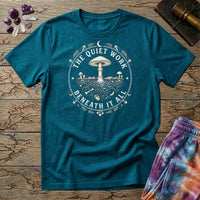 The Quiet Work Beneath It All badge with a mushroom above the soil line and its roots below, on a Tropical Blue unisex t-shirt