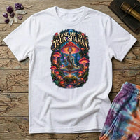 Take Me to Your Shaman lettering above a neon amanita-crowned figure meditating in a glowing forest, on a White unisex t-shirt