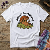 Mushroom in sunglasses kicked back on moss with a coffee, under Actively Decomposing lettering, on a unisex t-shirt