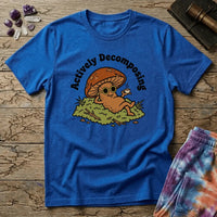 Mushroom in sunglasses kicked back on moss with a coffee, under Actively Decomposing lettering, on a unisex t-shirt