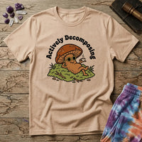 Mushroom in sunglasses kicked back on moss with a coffee, under Actively Decomposing lettering, on a unisex t-shirt