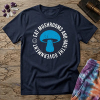 Distressed blue mushroom badge ringed by circle text and a small smiley face, on a unisex t-shirt