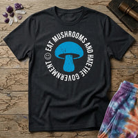 Distressed blue mushroom badge ringed by circle text and a small smiley face, on a unisex t-shirt